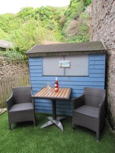 a picnic table and two chairs in front of a blue shed at The Cuddy - Apartment with garden in Brixham