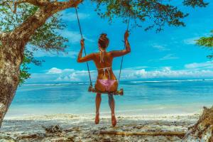 une femme sur une balançoire sur la plage dans l'établissement Mala Garden Resort and Spa, à Gili Trawangan