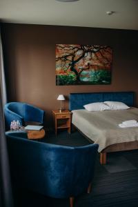 um quarto com uma cama e uma cadeira azul em Comfort Hotel Kuldiga em Kuldīga