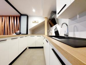 a kitchen with white cabinets and a black sink at Mes Amours in Ribeauvillé