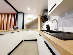 a kitchen with white cabinets and a black sink at Mes Amours in Ribeauvillé