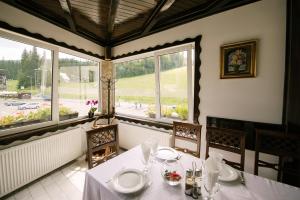 a dining room with a table and chairs and windows at Pensiunea Alpin Predeal in Predeal