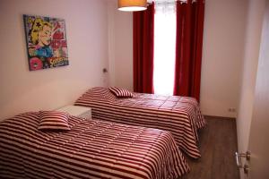 two beds in a room with red curtains and a window at Gîte Groseille in Ribeauvillé