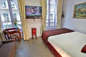 リヨンにあるオテル デ セレスタンのベッド、テレビ、窓が備わるホテルルームです。