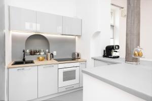 Biała kuchnia z białymi szafkami i zlewem w obiekcie Apartments Warsaw City Center by Noclegi Renters w Warszawie +34 zdjęcia