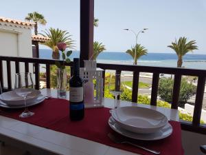 a table with plates and a bottle of wine on a balcony at Playa del Duque in 1st sea line directly on the beach, heated pool, Wifi, balcony in Adeje