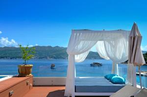 a bed on a deck with a view of the water at Kalamota Beach House in Koločep