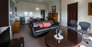sala de estar con sofá de cuero negro y mesa en Casa Rural en Cigarral de Villamarta Toledo con piscina y WIFI, en Toledo