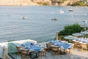 a group of tables and chairs next to a body of water at Lindos Royal Resort in Líndos