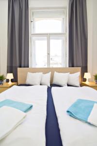 two white beds in a room with a window at Apartments in Mala Strana - 10 minutes from Charles Bridge in Prague