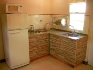 a kitchen with a white refrigerator and a sink at Casa de Montaña Sacha Huasi in Tafí del Valle