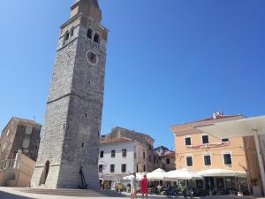 a tall tower in a city with people standing around it at Apartments Paris in Umag
