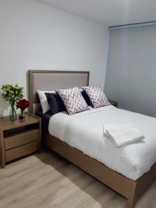 1 dormitorio con 1 cama y 1 mesa con flores en Foresta Boutique Apartments, en Quito