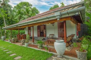 a house with a thatched roof and a patio at Villa Godahena in Ambalangoda