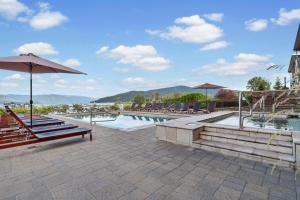 a swimming pool with chairs and an umbrella at Seasons 331 - Penthouse in Sandpoint