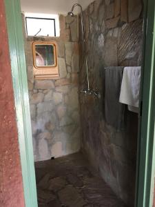 Baño de piedra con ducha y ventana en Nyangombe Backpackers, en Kwekwe