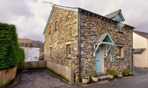 una casa in pietra con una porta blu su una strada di Thomas Fold Cottage ad Ambleside