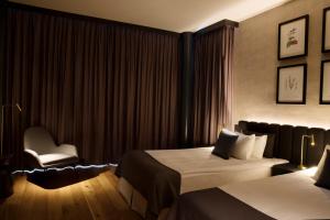 a hotel room with two beds and a chair at H&oacute;tel Reykjav&iacute;k Grand in Reykjav&iacute;k
