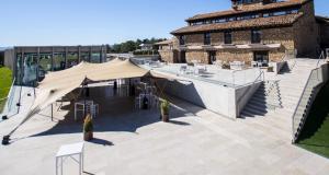 un patio con un edificio dotato di tenda e tavoli. di Hotel Restaurante Masía la Torre a Mora de Rubielos