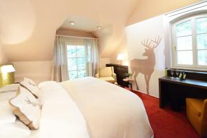 a bedroom with a white bed with a deer stencil on the wall at Romantik Hotel Jagdhaus Waldfrieden in Bilsen