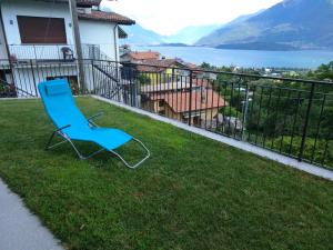 a blue chair sitting on the grass on a balcony at Apartment Rosa Dei Venti in Gravedona