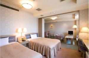 a hotel room with two beds and a desk at Highness Hotel Kurume in Kurume