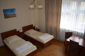 a room with two beds and a table and a window at Hostel Gwarek in Katowice