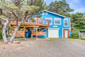 ein blaues Haus mit einer Terrasse und einem Baum in der Unterkunft Casa Blanca del Mar in Waldport