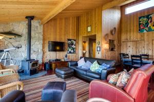 a living room with leather furniture and a stone wall at Bowsprit Retreat in Sea Ranch