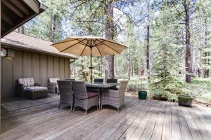 サンリヴァーにあるConifer Lane 01 | Discover Sunriverのテーブルと椅子と傘のあるパティオ