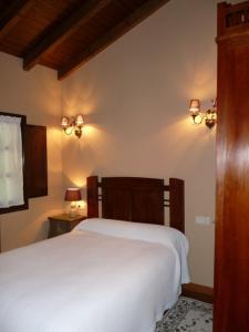 a bedroom with a white bed and two lights on the wall at Casa AL ABLUGO in Pola de Somiedo