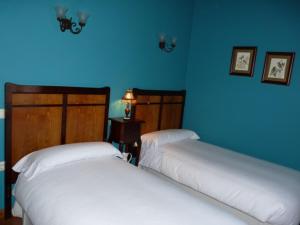 two beds in a room with blue walls at Casa AL ABLUGO in Pola de Somiedo