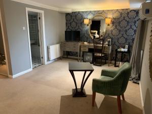 a living room with a table and a chair and a mirror at Barons Court Hotel Walsall in Walsall +31 photos