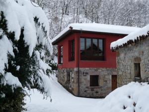 a red building with snow on top of it at Casa AL ABLUGO in Pola de Somiedo