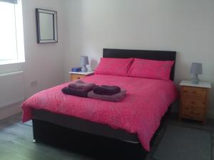 a bedroom with a pink bed with pink pillows at Casa Tara in Lahinch