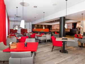 a dining room with red tables and chairs at DORMERO Hotel Zürich Airport in Glattbrugg