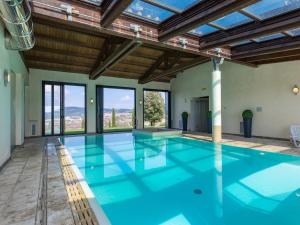 an indoor swimming pool with blue water and windows at Agriturismo Baccoleno in Asciano