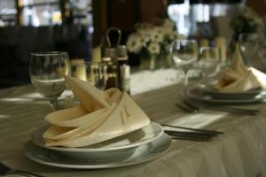 a table with plates and napkins on a table with wine glasses at Motel Maksumić in Jablanica
