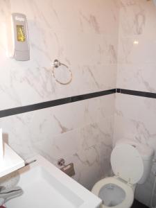 a bathroom with a toilet and a soap dispenser on the wall at Hotel Pacific in Paris