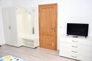 Cette chambre dispose d'une télévision sur une commode et d'une porte. dans l'établissement Carul cu Flori, à Sibiu