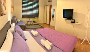 a bedroom with a purple bed and a tv at Cicki Apartments II in Podgorica