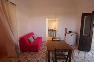 a living room with a red couch and a table at Bent el Rhia dammusi in Pantelleria
