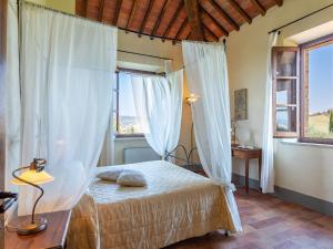 a bedroom with a bed with white curtains and a window at Agriturismo Baccoleno in Asciano