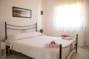 - une chambre dotée d'un lit avec des draps blancs et des fleurs dans l'établissement SOL LEONE, à Porto Torres
