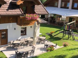 un patio con tavoli e sedie e un parco giochi di Hotel Sogni D'Oro a Camporosso in Valcanale