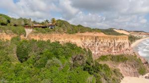 a house on top of a cliff next to the ocean at Hotel Ponta do Madeiro in Pipa