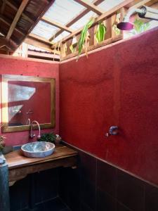 Baño rojo con lavabo y espejo en Harry's Ocean House Pacitan, en Pacitan