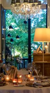 a table with glasses and a lamp and a window at Charmehotel Manoir Ogygia in Poperinge