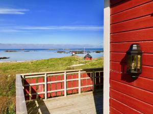 a red house with a balcony with a view of the water at Beach View Lofoten in Bøstad