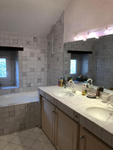 a white tiled bathroom with two sinks and a tub at Las Canéres in Castelnau-dʼArbieu